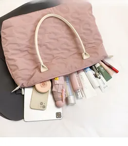 Flat lay of pink quilted nylon tote bag showcasing large capacity with travel essentials