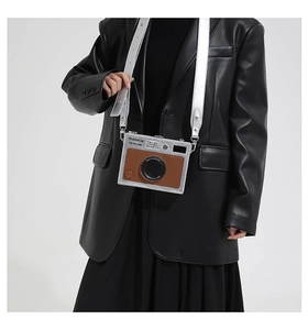 Detail of silver camera-shaped crossbody bag with brown lychee pattern and adjustable strap