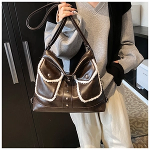 Close-up of brown PU leather shoulder bag with white faux fur trim and silver rivets
