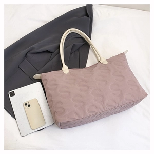 Detailed shot of pink quilted tote bag with S-pattern stitching and ivory leather handles