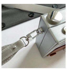 Detailed close-up of the silver metal lobster clasp and PU strap of the camera-shaped bag