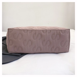 Detail of pink tote bag showing waterproof nylon fabric and S-shaped embossed pattern