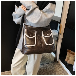 Detail of dark brown PU leather shoulder bag featuring plush fur trim and silver rivets