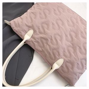 Detailed close-up of S-shaped quilting pattern and zipper closure on a pink tote bag