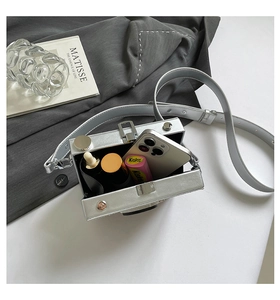 Detail of silver camera-shaped crossbody bag showing interior space for phone and makeup