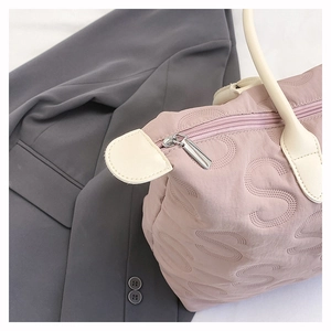Detail of S-pattern quilted tote bag featuring silver zipper and white leather trim
