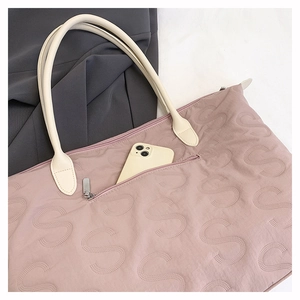 Detail view of pink quilted tote bag with side zipper and phone storage pocket