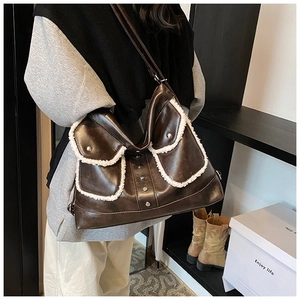 Detail of dark brown PU leather shoulder bag with white fleece trim and silver rivets