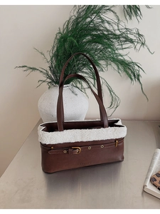 Detail of deep brown PU tote with white faux fur trim and gold buckle accents
