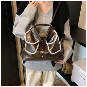Detail of dark brown faux leather shoulder bag with white fleece trim and metal buckles