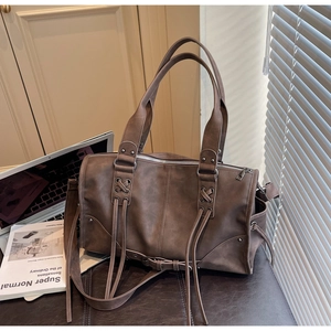 Détail d'un sac Boston vintage marron foncé avec de longues franges et détails argentés