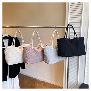 Detail of four quilted tote bags in white, pink, grey and black with S-pattern texture
