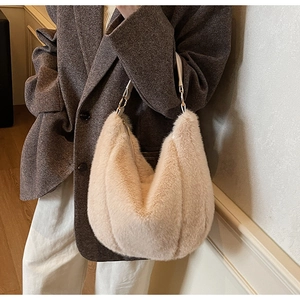 Close-up of plush faux fur shoulder bag in cream with leather strap on a model