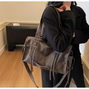 Détail d'un sac cabas vintage marron foncé en similicuir avec cordon à glands et œillets
