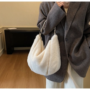 Close-up of white plush hobo bag with a leather handle worn with a grey oversized blazer