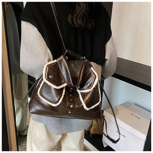 Detail of dark brown faux leather crossbody bag with plush white trim and metal studs