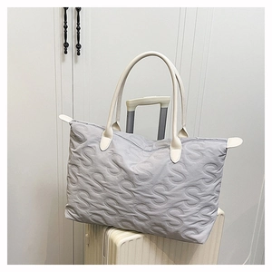 Close-up of quilted S-letter texture on large grey nylon tote bag with leather handles