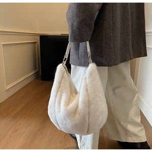 Close-up of white plush hobo bag with leather strap and golden hardware on model