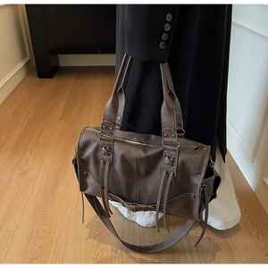 Détail d'un sac cabas marron vintage avec lacets croisés et longues franges en cuir