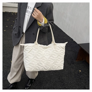 Detail of white quilted tote bag with S-shaped stitching and glossy finish texture