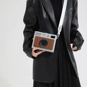 Retro camera-shaped crossbody bag with silver frame and brown texture worn by a model