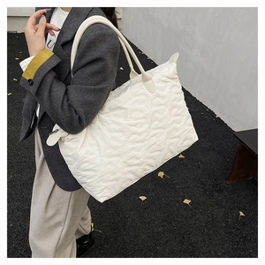 Close-up of white quilted tote bag with wave texture and zipper closure in street setting