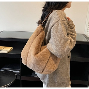 Detail of plush brown faux fur tote bag showing the leather shoulder strap and gold hardware