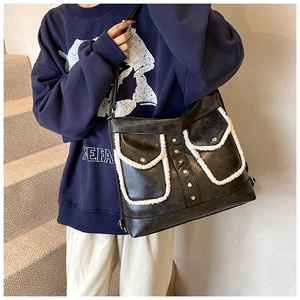Detail of black PU shoulder bag with white faux fur trim and silver rivet pockets