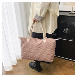 Macro detail of pink quilted tote bag with S-shape stitching and cream leather handles