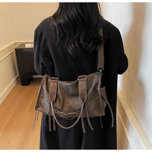 Détail d'un sac à main rétro en cuir marron foncé avec des franges et des boucles en métal