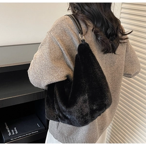 Detail of plush black faux fur shoulder bag with leather strap and metal ring attachments