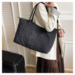 Close-up of black quilted tote bag featuring stylish S-letter embossed pattern texture