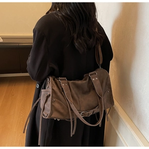 Détail du sac cabas marron vintage avec clous et franges porté à l'épaule