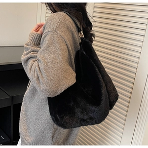 Detail view of large black plush faux fur tote bag with leather strap and gold buckle