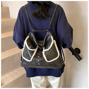Detail of vintage black leather backpack with sherpa trim and metal rivet accents