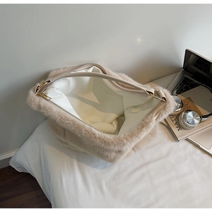 Top view of spacious interior of beige plush tote bag with gold zipper and stylish props