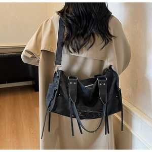 Détail du sac à bandoulière vintage noir avec rivets et lanières sur le dos du mannequin