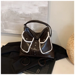 Detail of dark brown tote bag with white faux shearling pockets and silver metal rivets