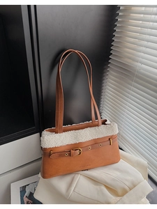 Detail of a brown PU leather shoulder bag with white faux shearling trim and buckle strap