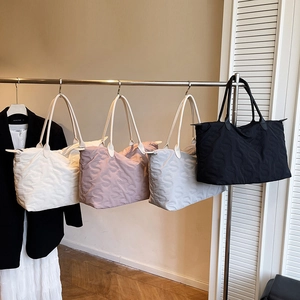 Quilted tote bags with S-letter pattern hanging in four stylish colors for commuting