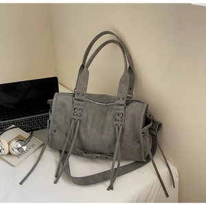 Vue détaillée du sac cabas gris vintage à pompons sur bureau blanc avec un ordinateur