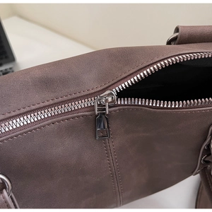 Gros plan sur la fermeture éclair et le cuir mat marron foncé du sac fourre-tout