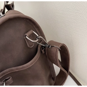 Détail du crochet en métal noir et bandoulière sur sac de transport marron foncé
