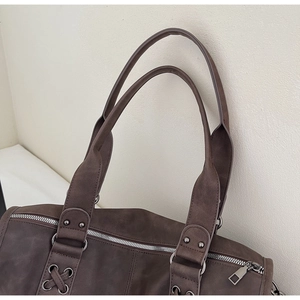 Détail du grand sac cabas marron foncé montrant la texture cuir mat et les rivets
