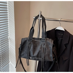 Détail d'un sac cabas rétro gris foncé avec des franges et des œillets métalliques