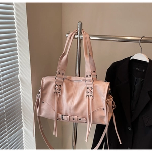 Gros plan sur un sac Boston rose pâle avec lanières décoratives en cuir et finition mate