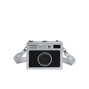 Macro shot of silver hardshell camera-style crossbody bag with influencer lens detailing