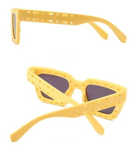 Detail view showing unique square hollow frame design and side profile of yellow sunglasses