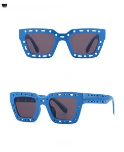 Detail of blue rectangular sunglasses with unique hollowed-out frame and dark lenses