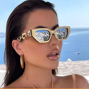 Detail of gold textured cat-eye sunglasses with bold metal chain temples and frame texture